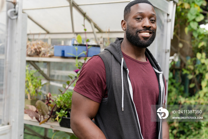 Portrait of smiling man standing in front of greenhouse