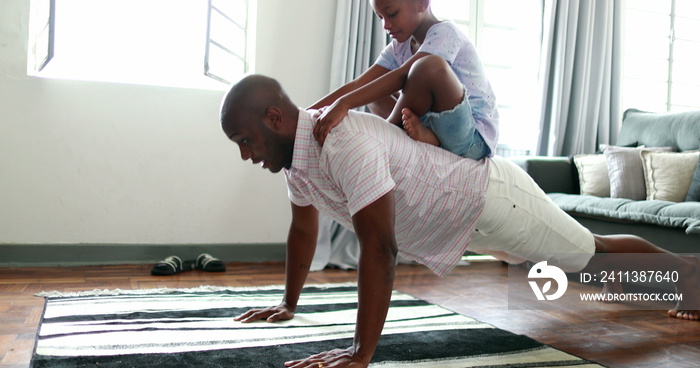 Father and child bonding together, dad doing push-ups with son in back