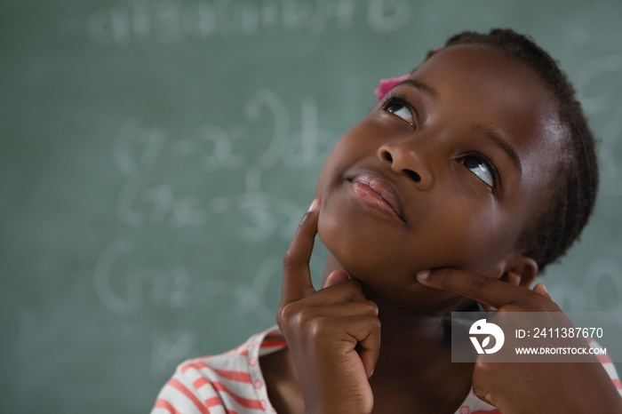 Schoolgirl sitting against chalkboard