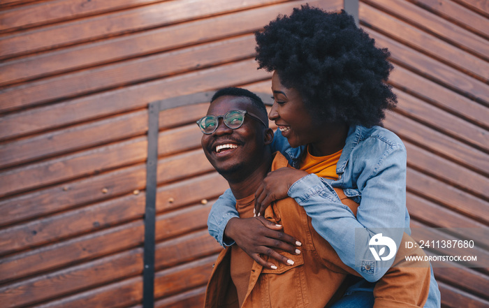 Young gorgeous hipster african couple having piggyback outdoors and having great time.