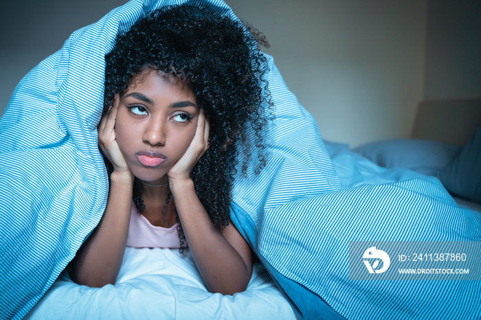 Pensive black woman trying to sleep in bed suffering from insomnia