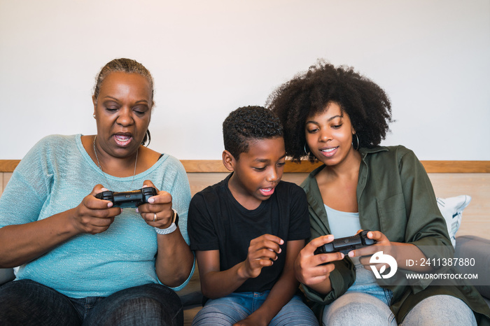 Grandmother, mother and son playing video games at home.