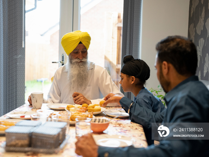 Three-generation family (6-7) having traditional meal at home