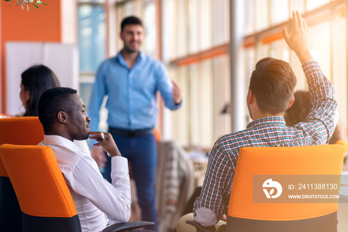 Young colleagues raising hands at the business meeting in office