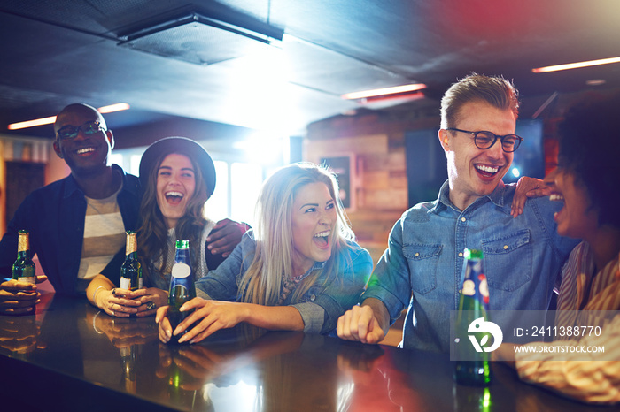 Laughing people sitting with drinks in bar