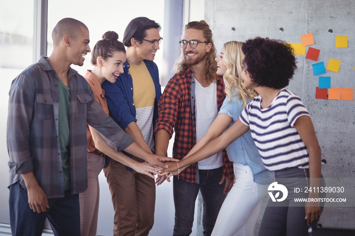 Cheerful business people stacking hands in creative office