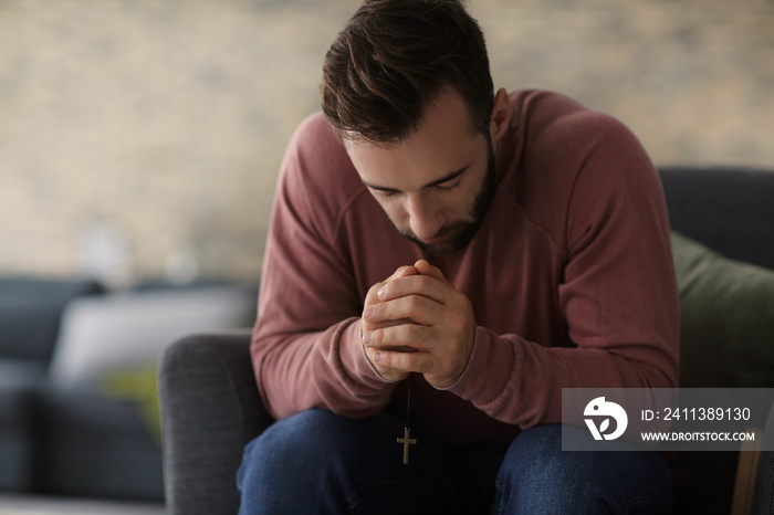 Religious young man praying to God at home