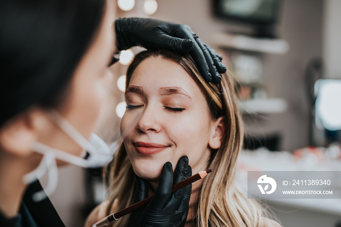 Eyebrows microblading concept. Cosmetologist preparing young woman for eyebrow permanent makeup procedure.