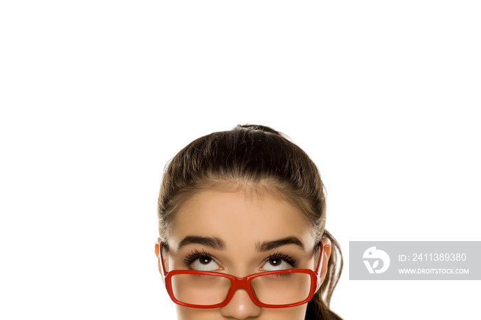 Young confused woman with glasses looking up on white background