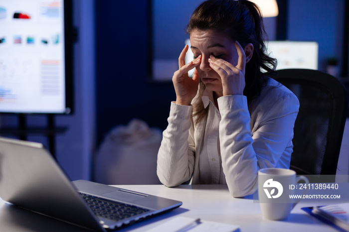 Stressed manager woman massaging tired eyes while sitting at workplace in start-up office working . Businesswoman overworking for analysing finance network to respect deadline.