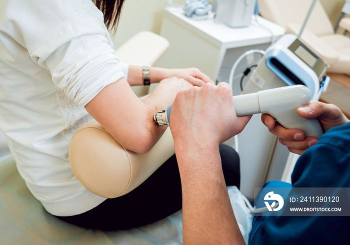 Shock wave therapy. The magnetic field, rehabilitation. Physiotherapist doctor performs surgery on a patient’s elbow