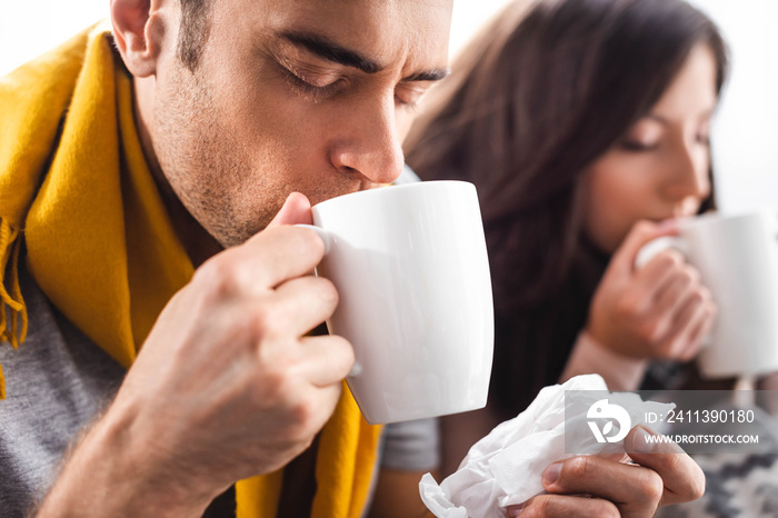 Selective focus of sick boyfriend drinking tea and holding napkin