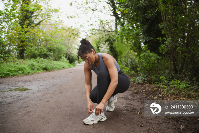 Young curvy woman with vitiligos in workout clothes tying her shoelaces