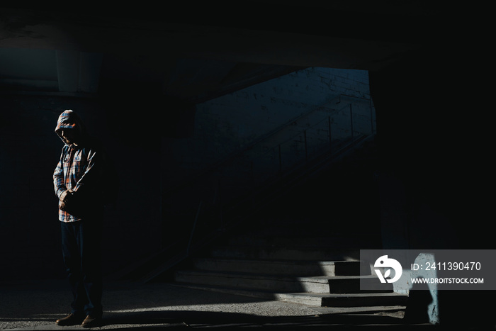 Man sits on the ground in darken tunnel