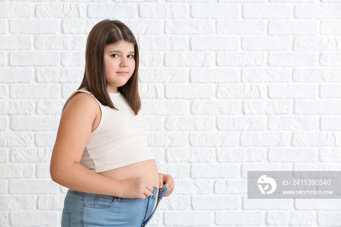 Overweight girl in tight clothes on white brick background