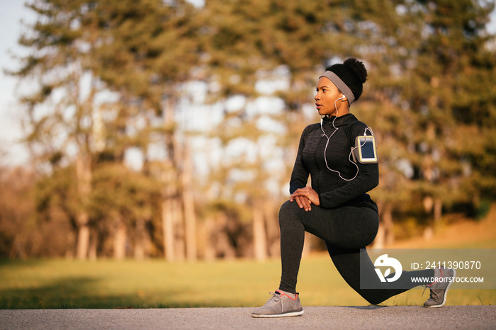 Mid adult black sportswoman stretching in the park.