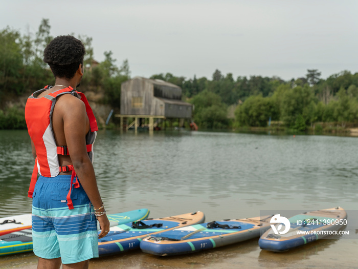 Young man looking at lake before paddleboarding