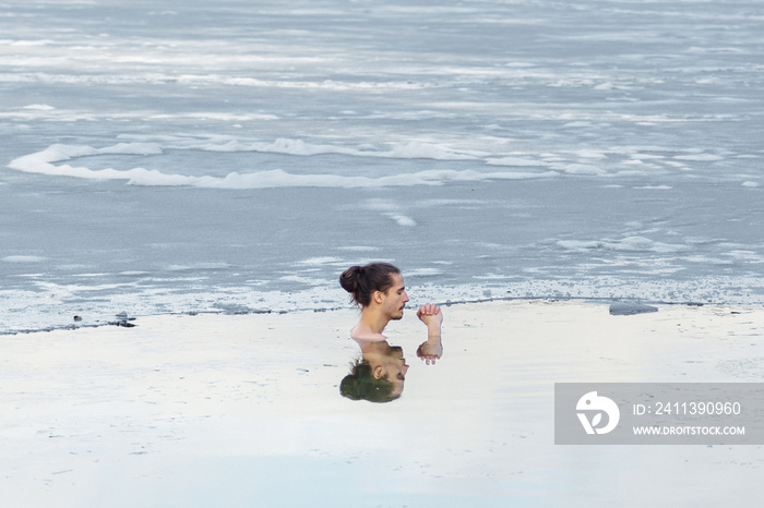 Boy or man ice bathing in the cold water of a lake. Wim Hof Method, cold therapy, breathing techniques, yoga and meditation