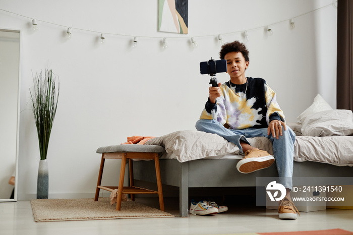 Full length portrait of young black teenager filming story for social media at home, copy space