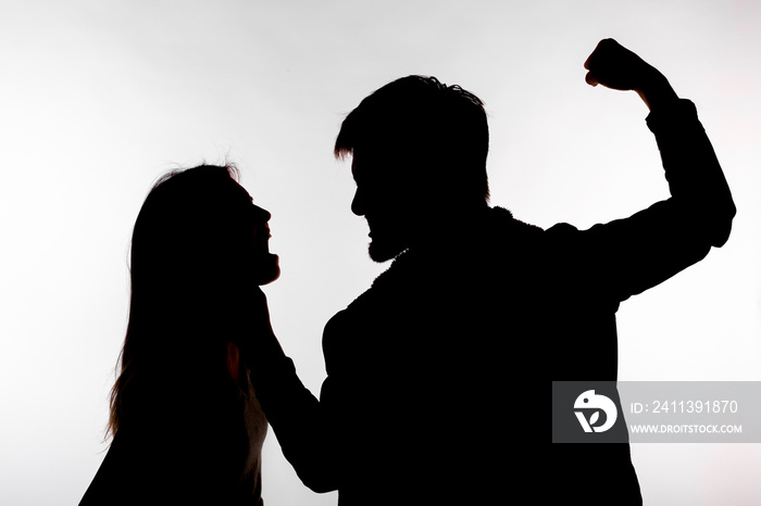 Domestic violence and abuse concept - Silhouette of man beating defenseless woman