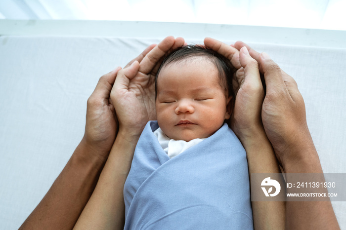 newborn baby with blanket in parent hands sleep on the bed. family baby protection concept