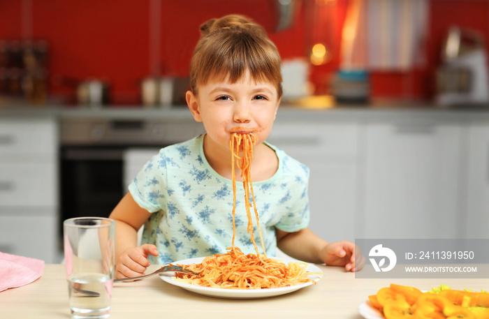 Adorable little girl eating spaghetti at table