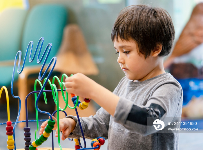 Indoor Portrait preschool boy playing in kid club with vintage tone, Child having fun playing colorful toys in kid playroom. Kid boy playing with educational toys in kindergarten. Education concept