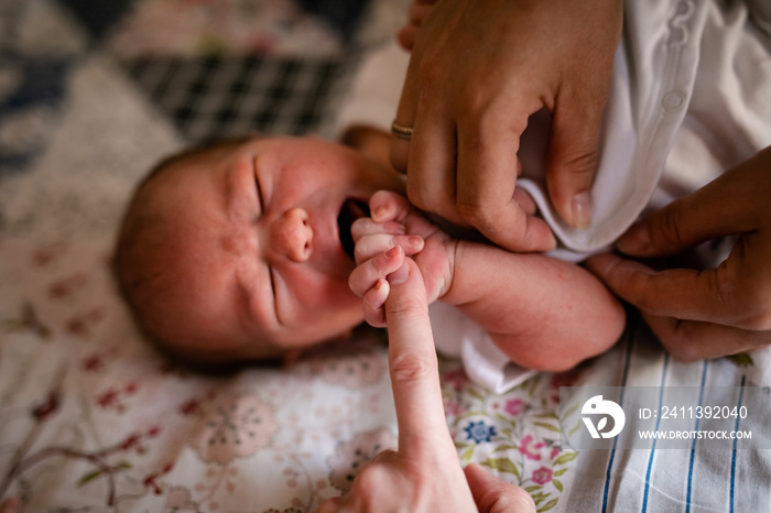 Newborn baby holding his mothers finger, selective focus