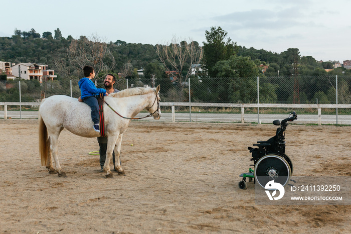 Child with disabilities sitting on the horse while having an equine therapy session.