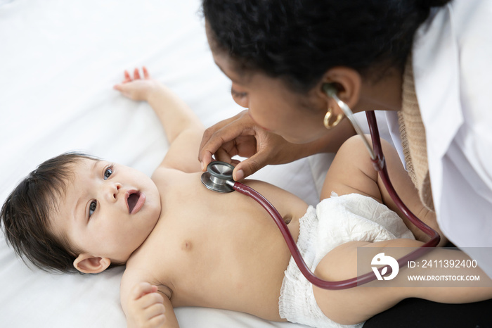 doctor using stethoscope for pediatrician examining baby tummy on the bed