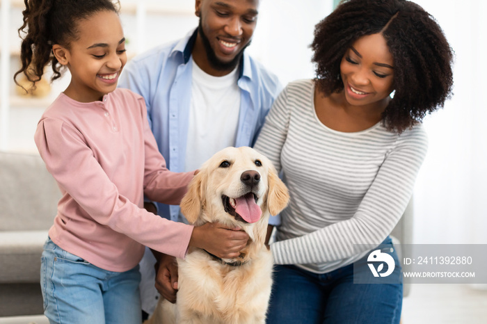 Young black family hugging dog posing at home