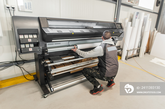 Technician operator changes paper roll on large printer plotter machine