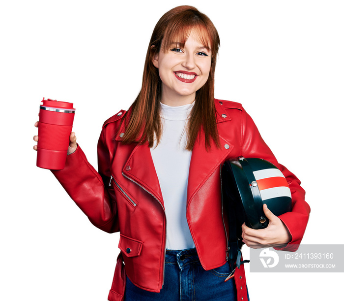 Redhead young woman holding motorcycle helmet and take away coffee smiling with a happy and cool smile on face. showing teeth.