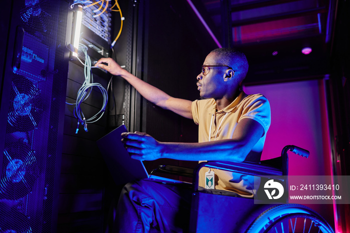 Side view portrait of person with disability working at system administrator in server room