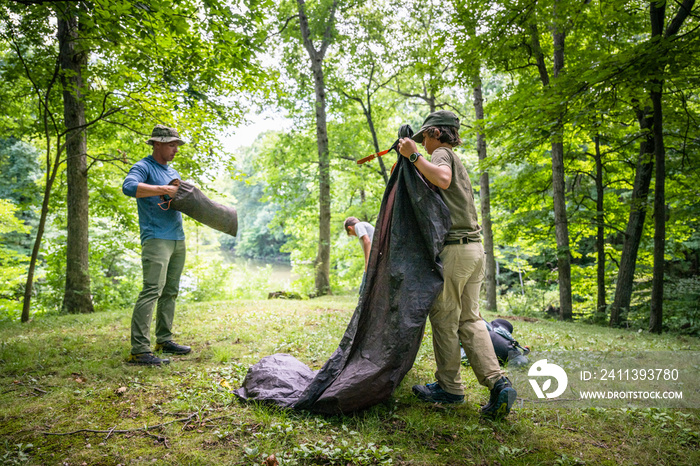 Air Force service member sets up a tent with his sons on  a backpacking trip.