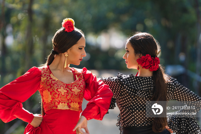 Two women in flamenco traditional costume dancing side by side outdoors