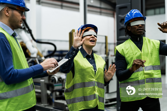 Team of engineers having simulation experience with futuristic virtual reality glasses inside robotic factory - Tech industry and metaverse concept