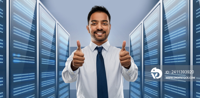 business, technology and data concept - smiling indian businessman in shirt with tie showing thumbs up over server room background