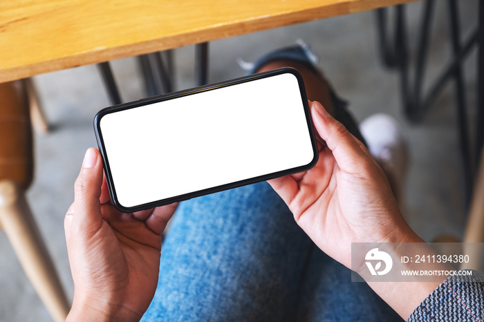 Top view mockup image of a woman holding mobile phone with blank white desktop screen