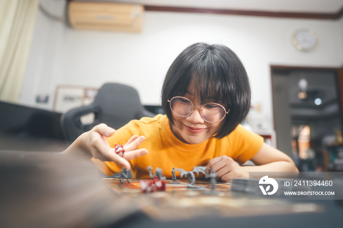 Happy young adult asian woman playing board game on top table at home