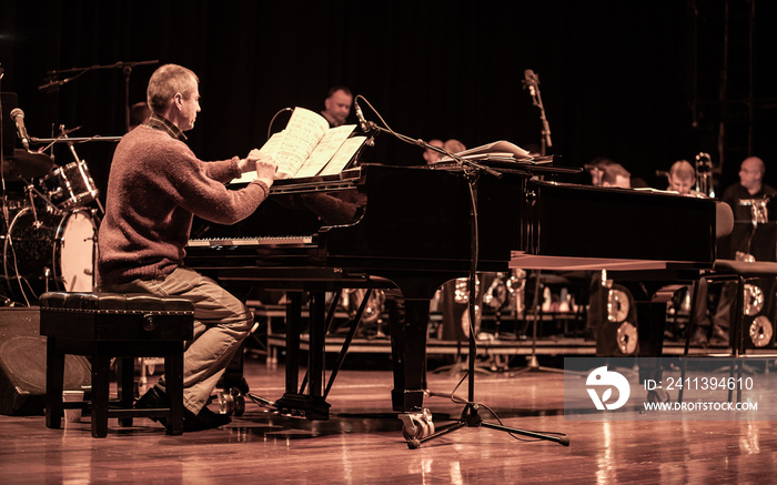 Big Band: jazz pianist. A piano player referring to his music in the studio. From a series of images of musicians in a swing Jazz band.