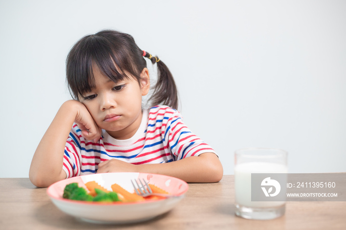 Nutrition & healthy eating habits for kids concept. Children do not like to eat vegetables. Little cute girl refuses to eat healthy vegetables.