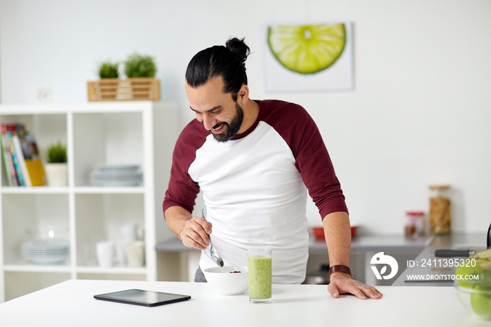 man with tablet pc eating breakfast at home