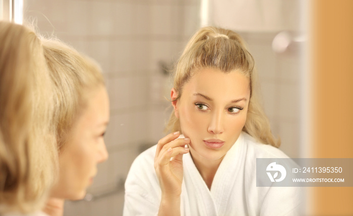 Woman looking in the mirror Applying the cream..Magic anti-aging cream