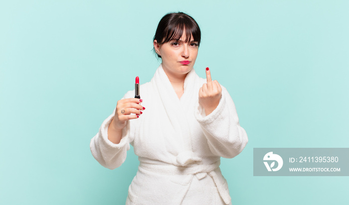 young woman wearing bathrobe feeling angry, annoyed, rebellious and aggressive, flipping the middle finger, fighting back