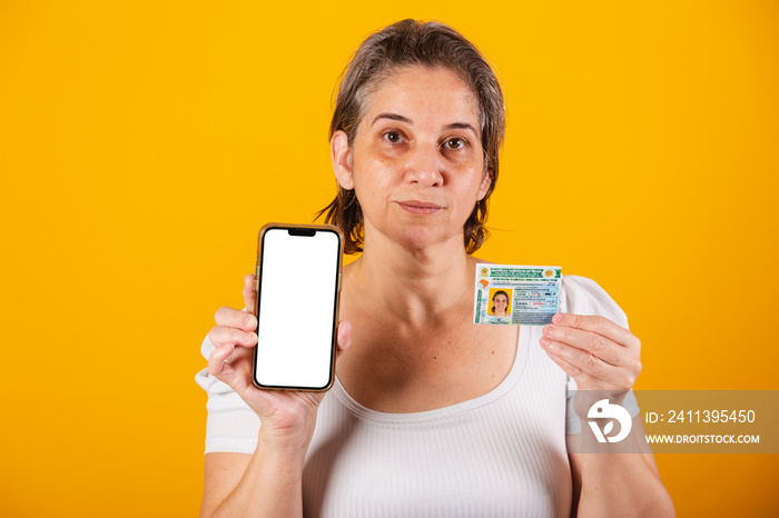 Adult Brazilian woman holding driver’s license and smartphone with green screen