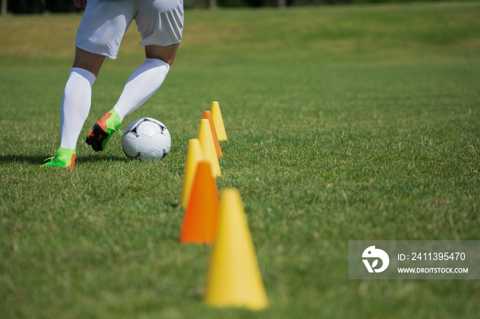 Soccer player dribbling through cones