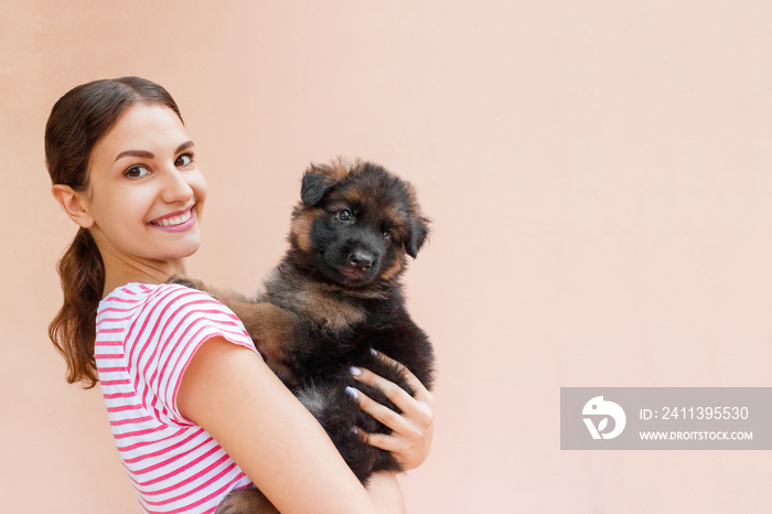 Happy young woman holding her pet puppy on orange background