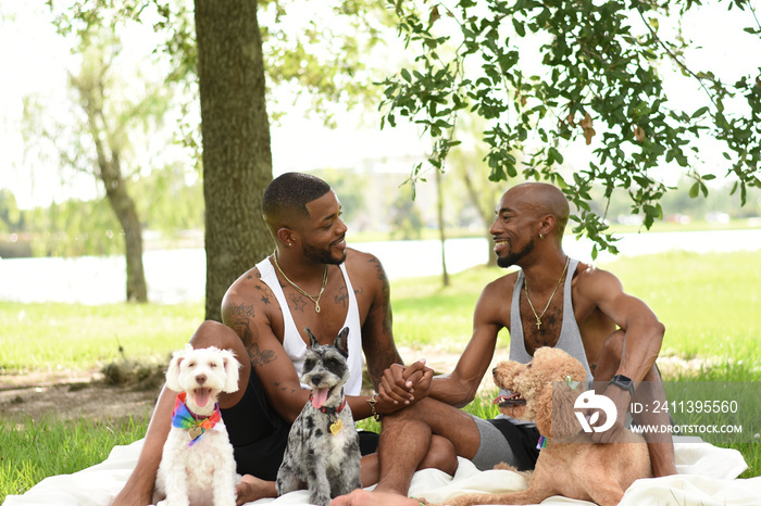 USA, Louisiana, Gay couple with dogs having picnic on lawn in park