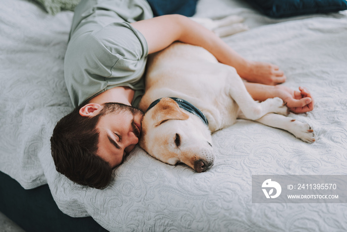 Pleasant young man enjoying his sleep while embracing his dog